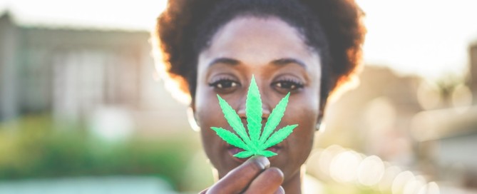 Young black girl holding marijuana leaf